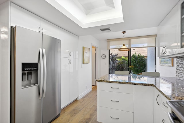 kitchen with stainless steel fridge with ice dispenser, white cabinetry, and dark stone countertops