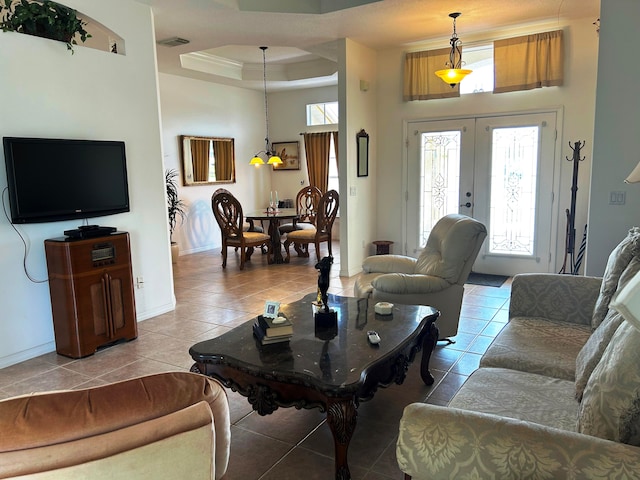 tiled living room with a towering ceiling, a tray ceiling, and french doors