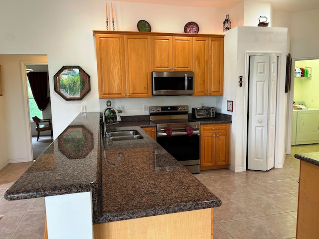 kitchen featuring stainless steel appliances, sink, washer and dryer, light tile patterned floors, and kitchen peninsula