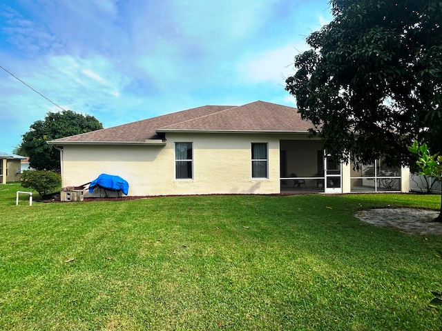 back of property featuring a sunroom and a lawn