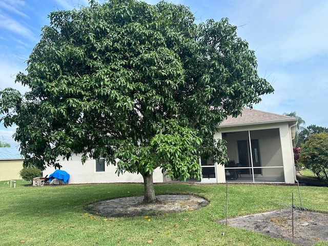 rear view of property with a lawn and a sunroom