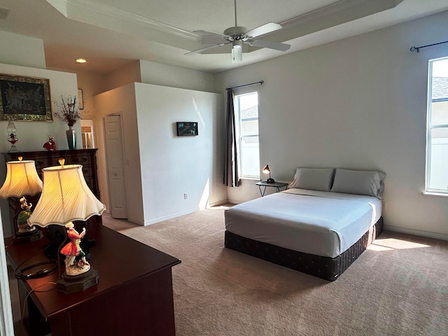 bedroom featuring ceiling fan, a raised ceiling, and light carpet