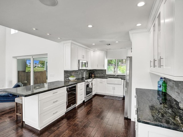 kitchen with wine cooler, appliances with stainless steel finishes, white cabinets, and sink