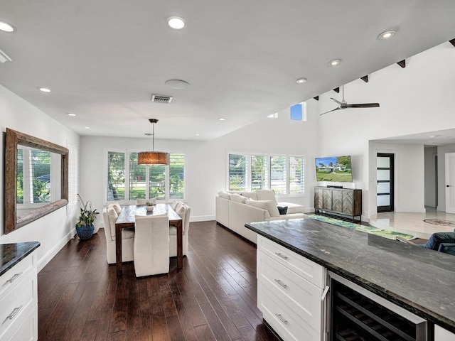 kitchen featuring ceiling fan, hanging light fixtures, dark stone countertops, wine cooler, and white cabinetry