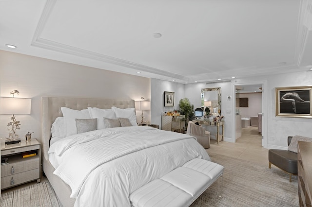 bedroom with a raised ceiling, light tile floors, and ensuite bathroom