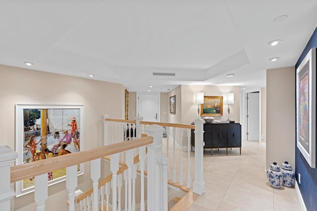 hallway with light tile floors and a tray ceiling