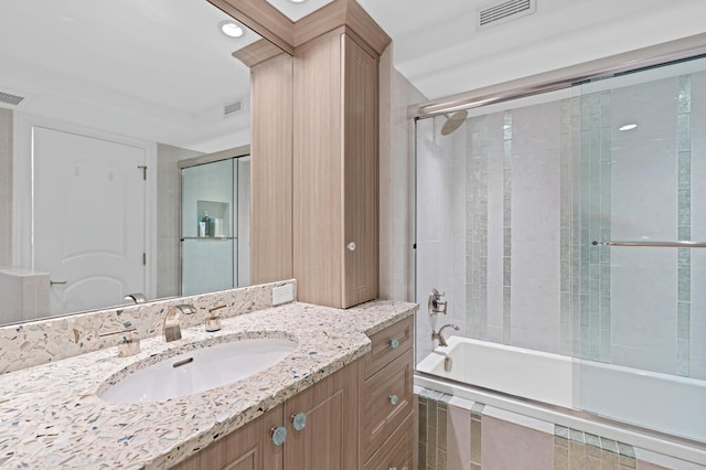 bathroom with vanity with extensive cabinet space and shower / bath combination with glass door