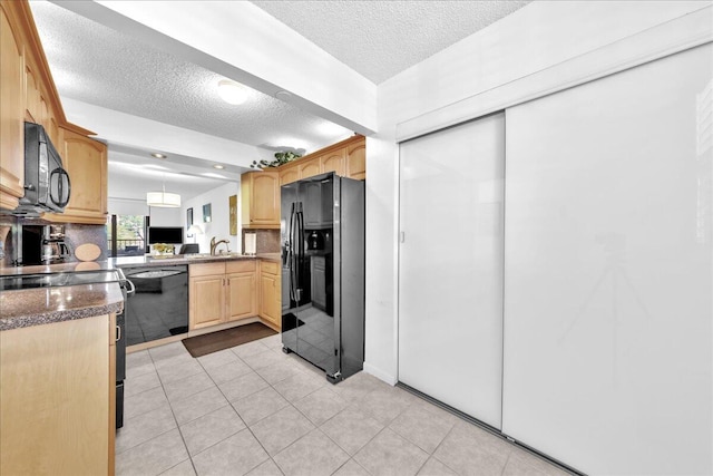 kitchen with decorative light fixtures, black appliances, light tile flooring, sink, and a textured ceiling