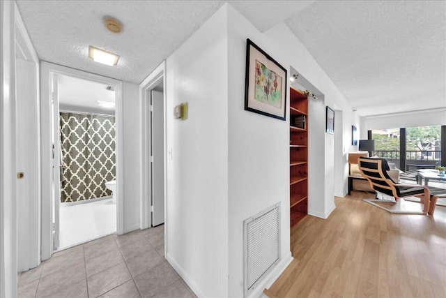 hall featuring a textured ceiling and light wood-type flooring