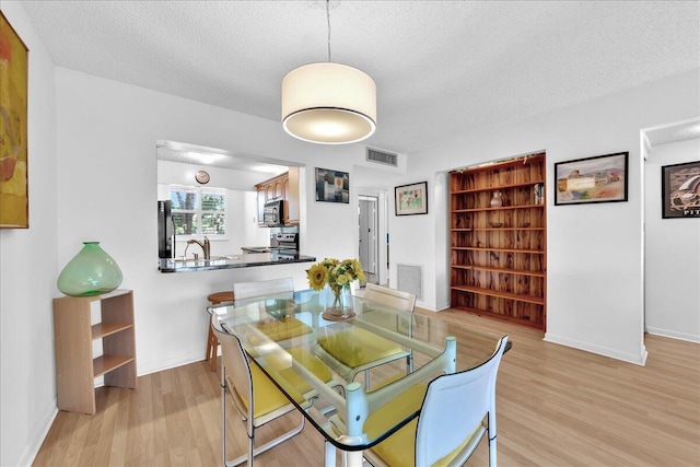 dining room featuring light hardwood / wood-style flooring, a textured ceiling, and sink