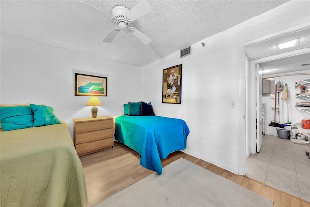 bedroom featuring ceiling fan, light tile floors, and a textured ceiling