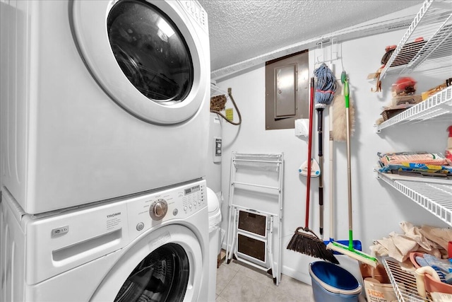 clothes washing area featuring light tile flooring, a textured ceiling, and stacked washer and clothes dryer