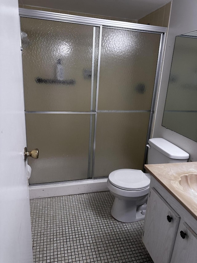 bathroom featuring toilet, tile patterned flooring, walk in shower, and vanity