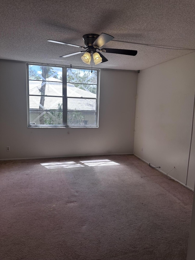 empty room featuring a textured ceiling, ceiling fan, and carpet