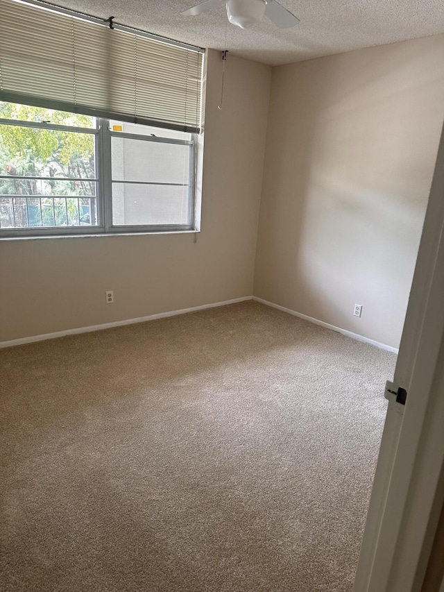 carpeted empty room with ceiling fan and a textured ceiling