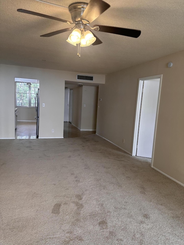 carpeted spare room featuring ceiling fan and a textured ceiling