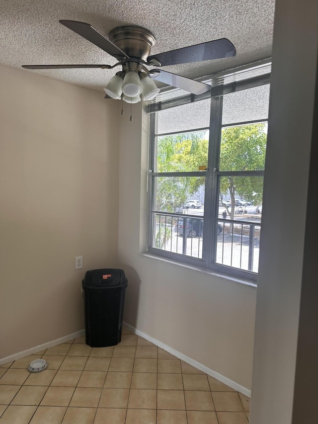 tiled empty room featuring a textured ceiling and ceiling fan