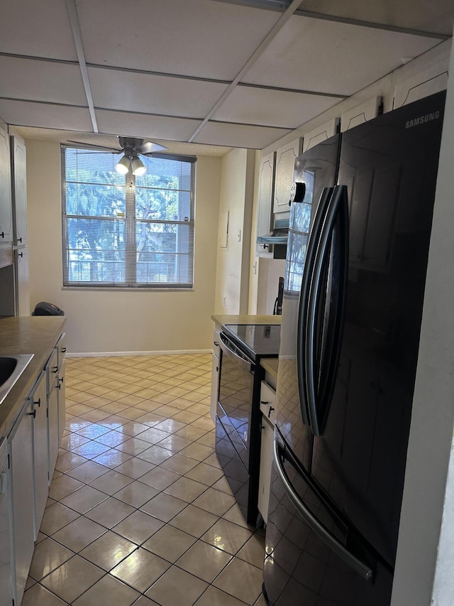 kitchen with ceiling fan, a drop ceiling, white cabinets, and black appliances