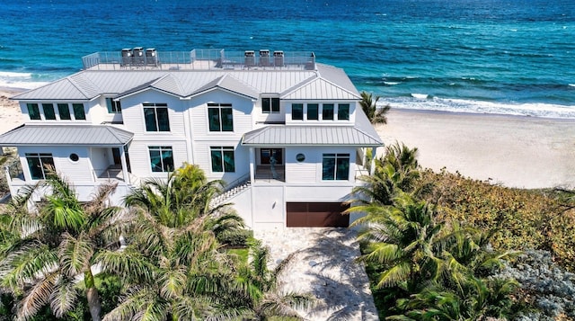 exterior space with a beach view, a garage, a balcony, and a water view