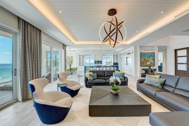 living room with a water view and a tray ceiling