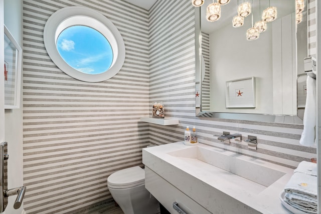 bathroom featuring an inviting chandelier, toilet, and large vanity