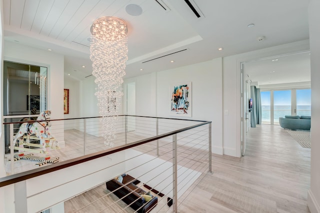 corridor featuring a water view, a chandelier, and light wood-type flooring