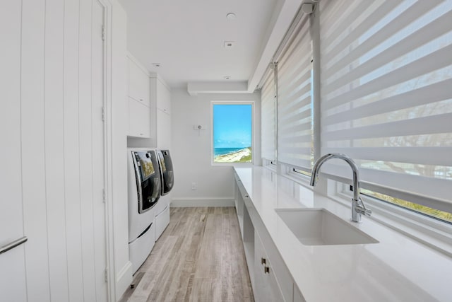 interior space with sink, light hardwood / wood-style flooring, and washing machine and clothes dryer