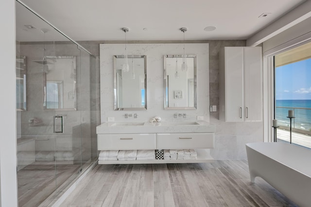 bathroom featuring tile walls, double vanity, independent shower and bath, and a water view