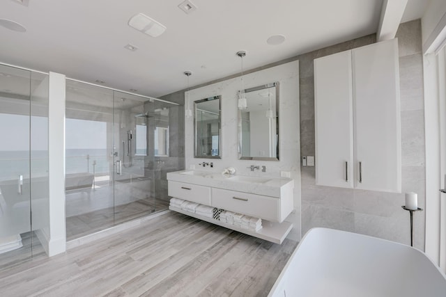 bathroom featuring tile walls, a water view, separate shower and tub, and oversized vanity