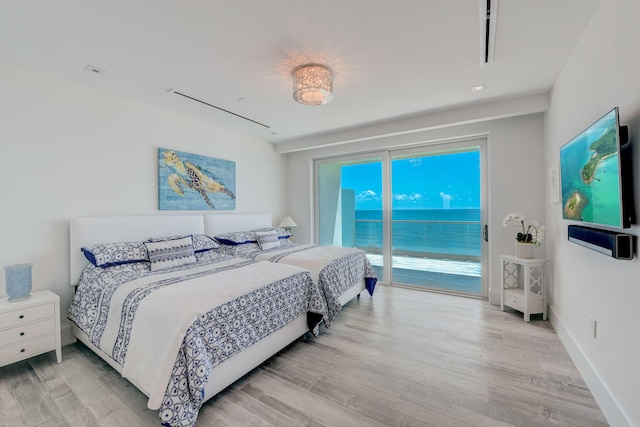 bedroom with access to outside, a water view, and light hardwood / wood-style flooring