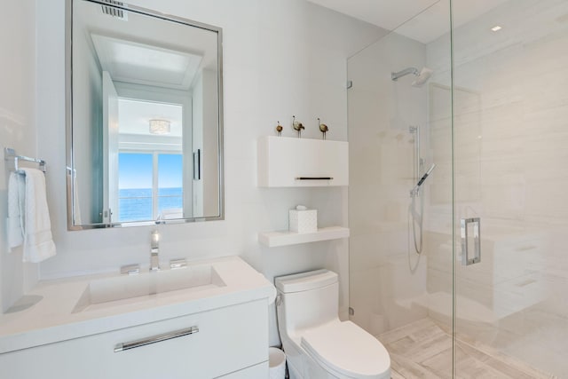 bathroom featuring a shower with door, a water view, toilet, and large vanity