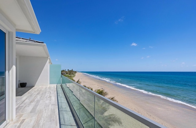 balcony featuring a view of the beach and a water view