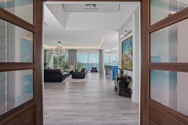 living room with a tray ceiling, a notable chandelier, and hardwood / wood-style flooring