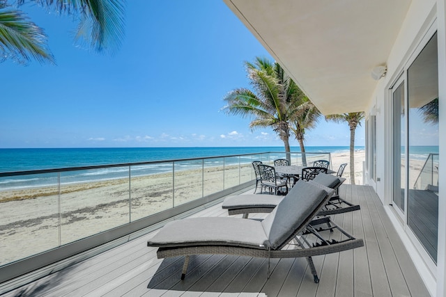 wooden deck featuring a view of the beach and a water view