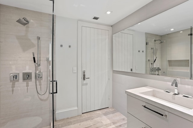 bathroom with a shower with door, wood-type flooring, and vanity