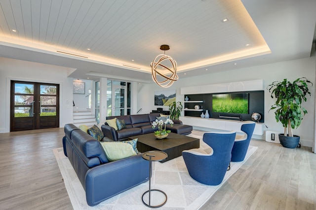 living room featuring wooden ceiling, french doors, light wood-type flooring, and a raised ceiling