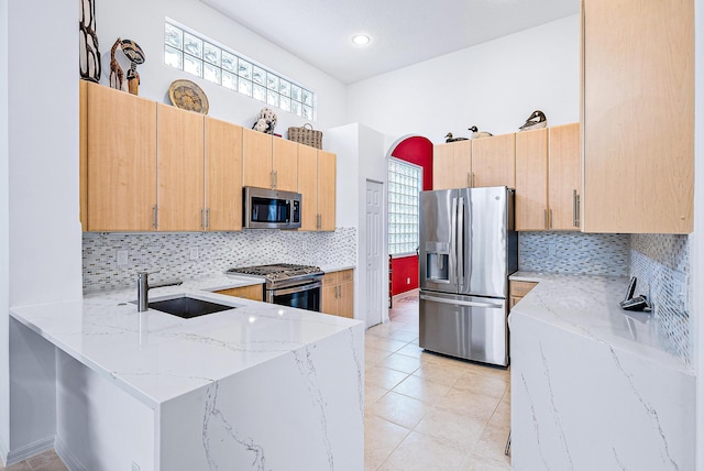 kitchen featuring appliances with stainless steel finishes, plenty of natural light, backsplash, and light stone counters