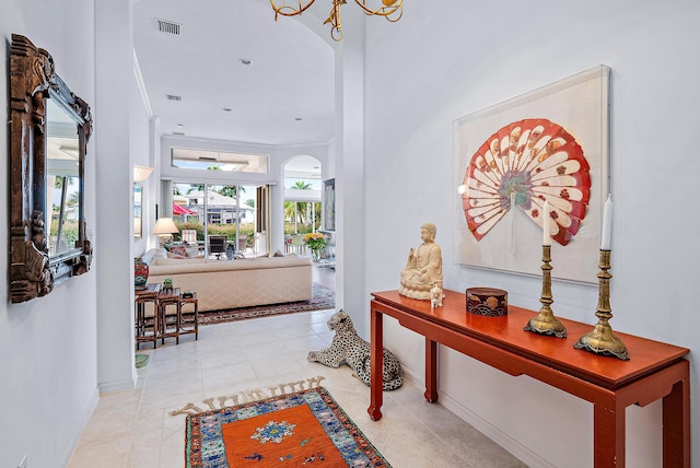 tiled foyer entrance with a notable chandelier and crown molding