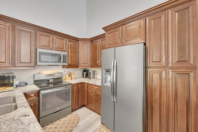 kitchen featuring light stone countertops, stainless steel appliances, and light hardwood / wood-style floors