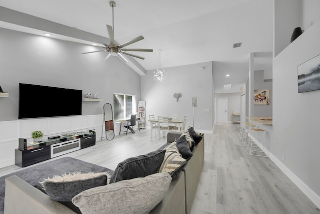 living room featuring high vaulted ceiling, light wood-type flooring, and ceiling fan with notable chandelier