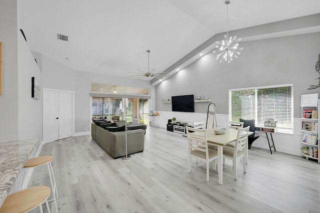 living room with high vaulted ceiling, a wealth of natural light, light wood-type flooring, and ceiling fan with notable chandelier