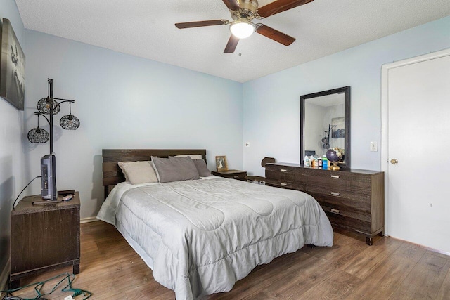 bedroom featuring ceiling fan, a textured ceiling, and dark wood-type flooring