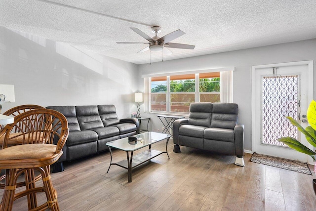 living room with light hardwood / wood-style floors, ceiling fan, and a textured ceiling