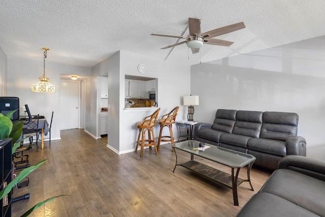 living room featuring a textured ceiling, ceiling fan, and hardwood / wood-style flooring