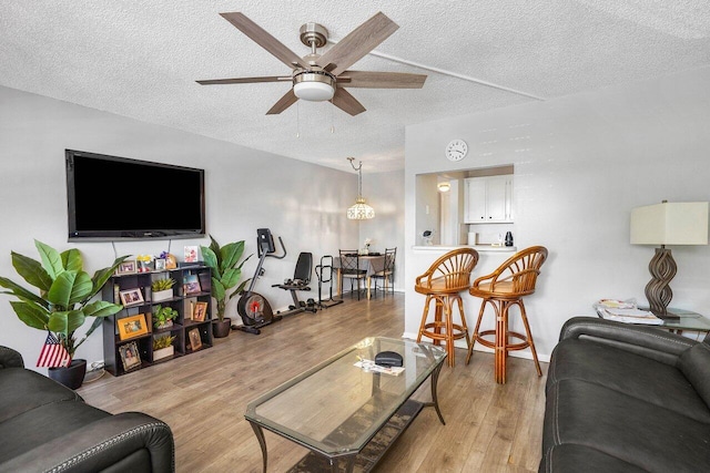 living room featuring a textured ceiling, ceiling fan, and light wood-type flooring