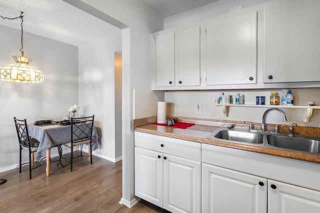 kitchen featuring white cabinets, dark wood-type flooring, sink, and pendant lighting