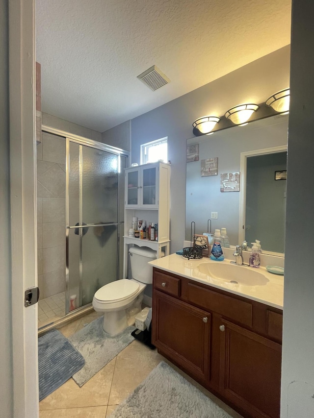 bathroom with tile patterned floors, walk in shower, a textured ceiling, vanity, and toilet