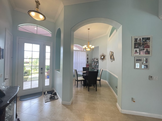 tiled foyer with crown molding and a notable chandelier