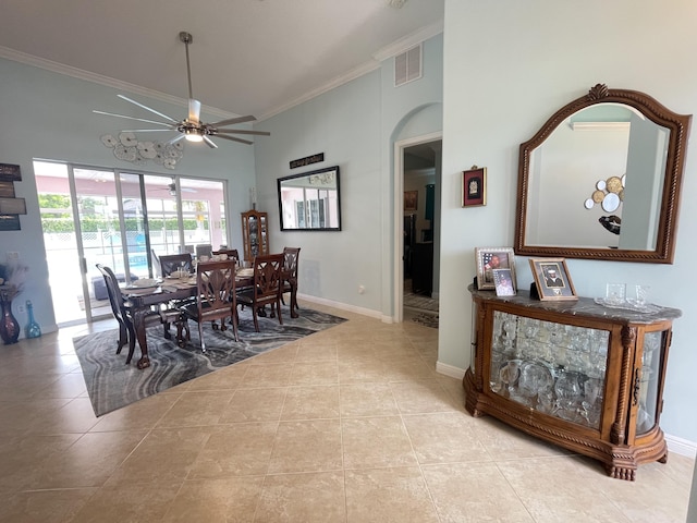 dining space with ceiling fan, light tile patterned flooring, ornamental molding, and a high ceiling