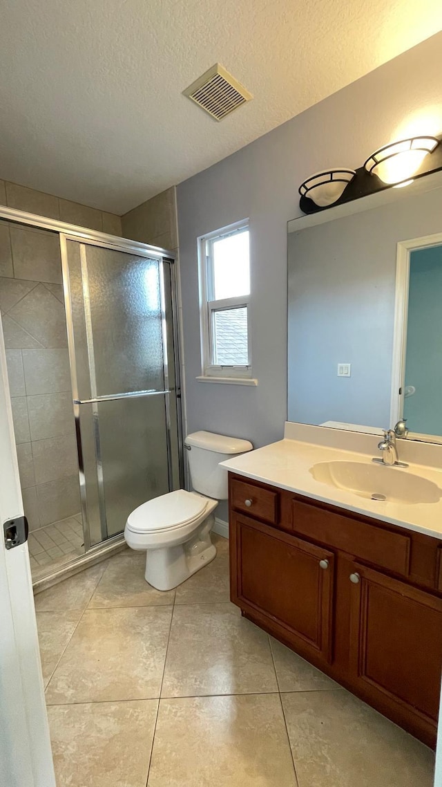 bathroom with a textured ceiling, vanity, toilet, and a shower with shower door